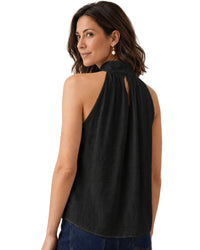 niffty black sleeveless satin top with a high neckline and back keyhole button closure worn by a woman