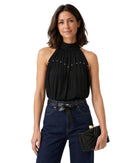 niffty black sleeveless satin top with high neck and stud details worn by a woman with dark denim jeans
