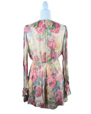 Back view of niffty Zimmermann silk romper in cream with pink and green floral print, long sleeves, and ruffled hem.