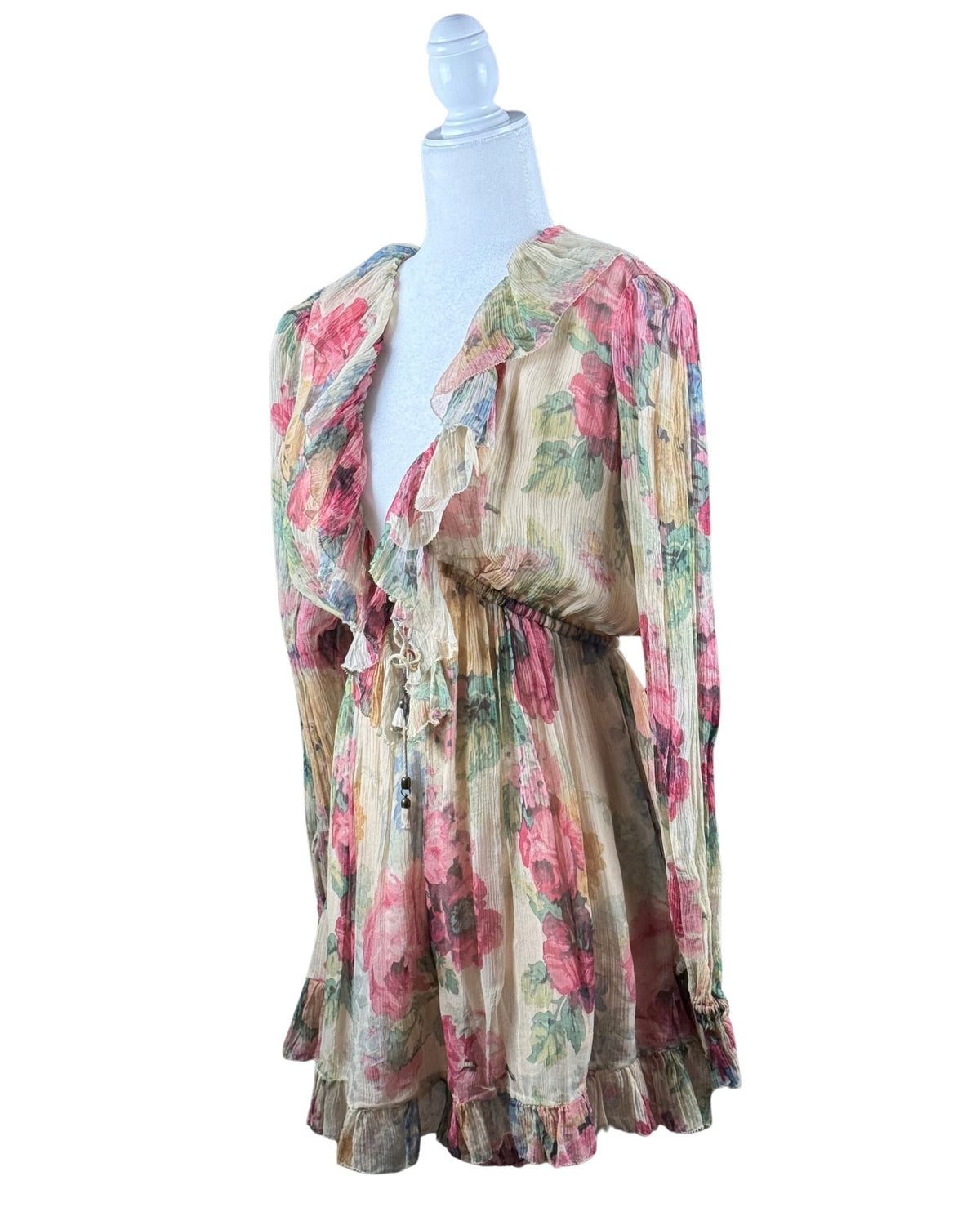 niffty Zimmermann silk romper in cream with pink and green floral print, featuring a deep V-neck and ruffled hems.